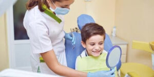 dental-assistant-showing-child-their-teeth-in-mirror