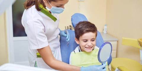 dental-assistant-showing-child-their-teeth-in-mirror
