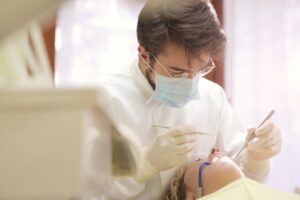 Photo by Andrea Piacquadio: https://www.pexels.com/photo/man-in-white-dress-shirt-wearing-white-framed-eyeglasses-3779705/ - dentist examining a patient’s teeth 