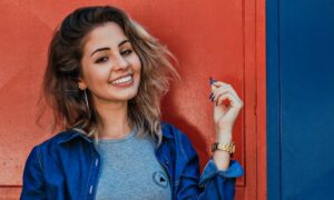 Image URL: Photo by Vinicius Wiesehofer: https://www.pexels.com/photo/photo-of-woman-wearing-blue-zip-up-jacket-1090387/ Alt Text: Young brunette smiling with a terra cotta background